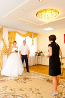 Специалист ЗАГСа торжественно вручает жениху с невестой свидетельство о заключении брака и Губернаторское поздравление молодоженам