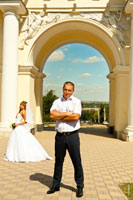 Фото жениха на переднем плане, невеста принимает поздравления по телефону вдали