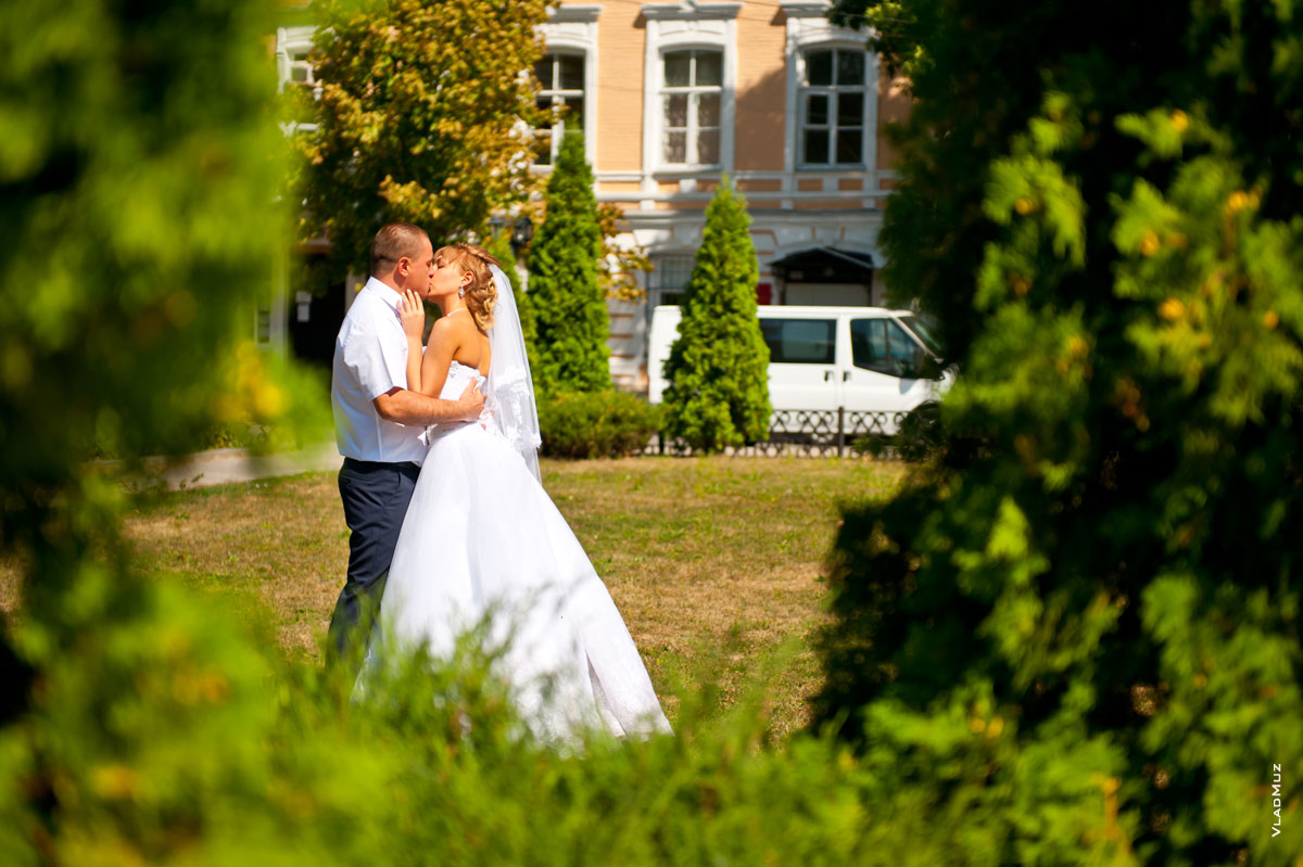 Фото поцелуя жениха и невесты среди туй у Атаманского дворца в Новочеркасске