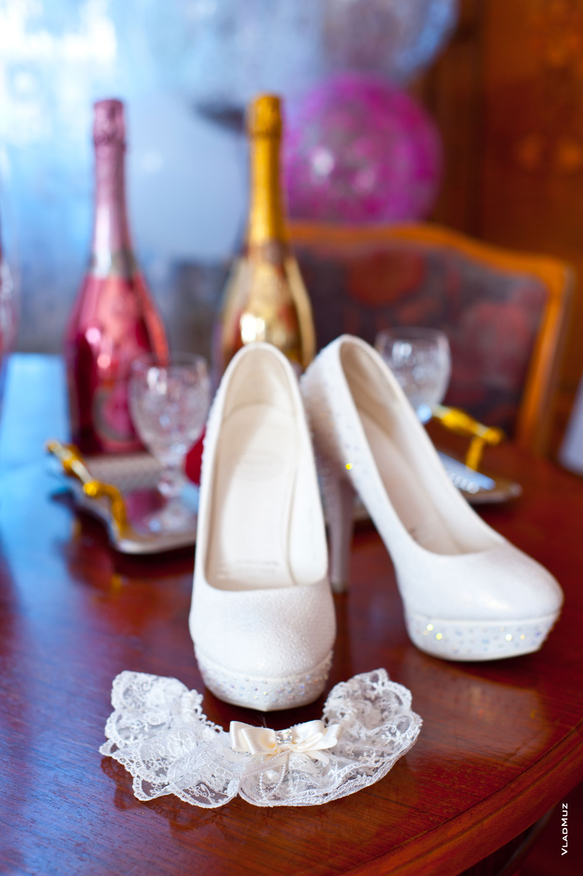Свадебный натюрморт: фото подвязки и белых туфель невесты на фоне бутылок шампанского и бокалов