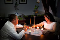 Фото невесты с женихом за столом с бокалами шампанского при свете свечей