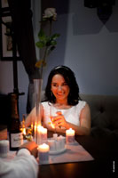 Фото красивой, улыбающейся невесты за столом с бокалом шампанского при свете свечей