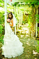 Фото невесты с веером и букетом в арке тенистой аллеи