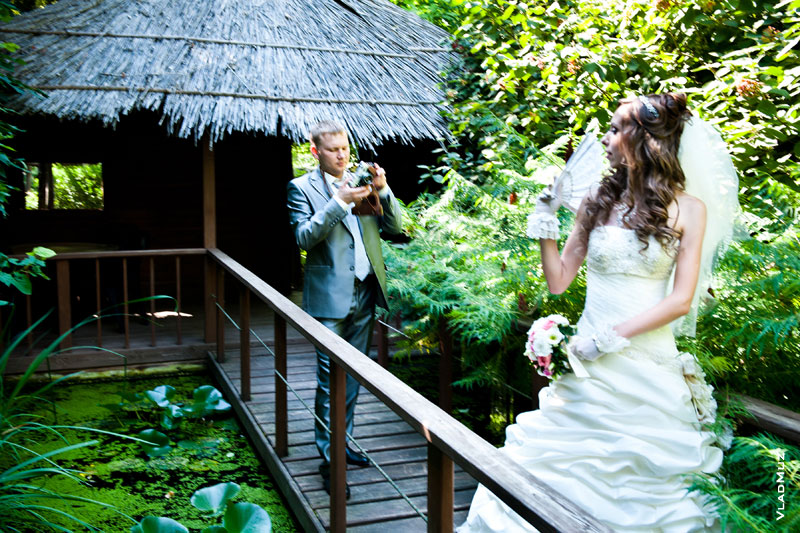 Фото жениха, фотографирующего невесту. Невеста позирует