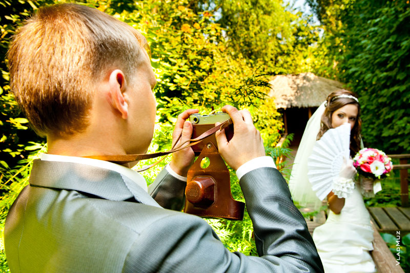 Фото жениха с фотокамерой в фокусе, а невесты — в расфокусе
