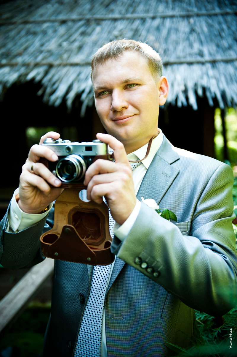 Фотопортрет жениха с фотокамерой во время фотосъемки