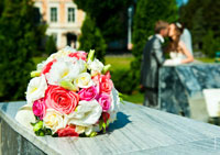Фото молодоженов у фонтана перед Атаманским дворцом: на переднем плане букет невесты в фокусе, а жених с невестой — в расфокусе