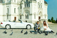 В кадре: жених с невестой кормят голубей. Белый кабриолет стоит вдали