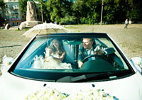 Жених с невестой внутри свадебного кабриолета