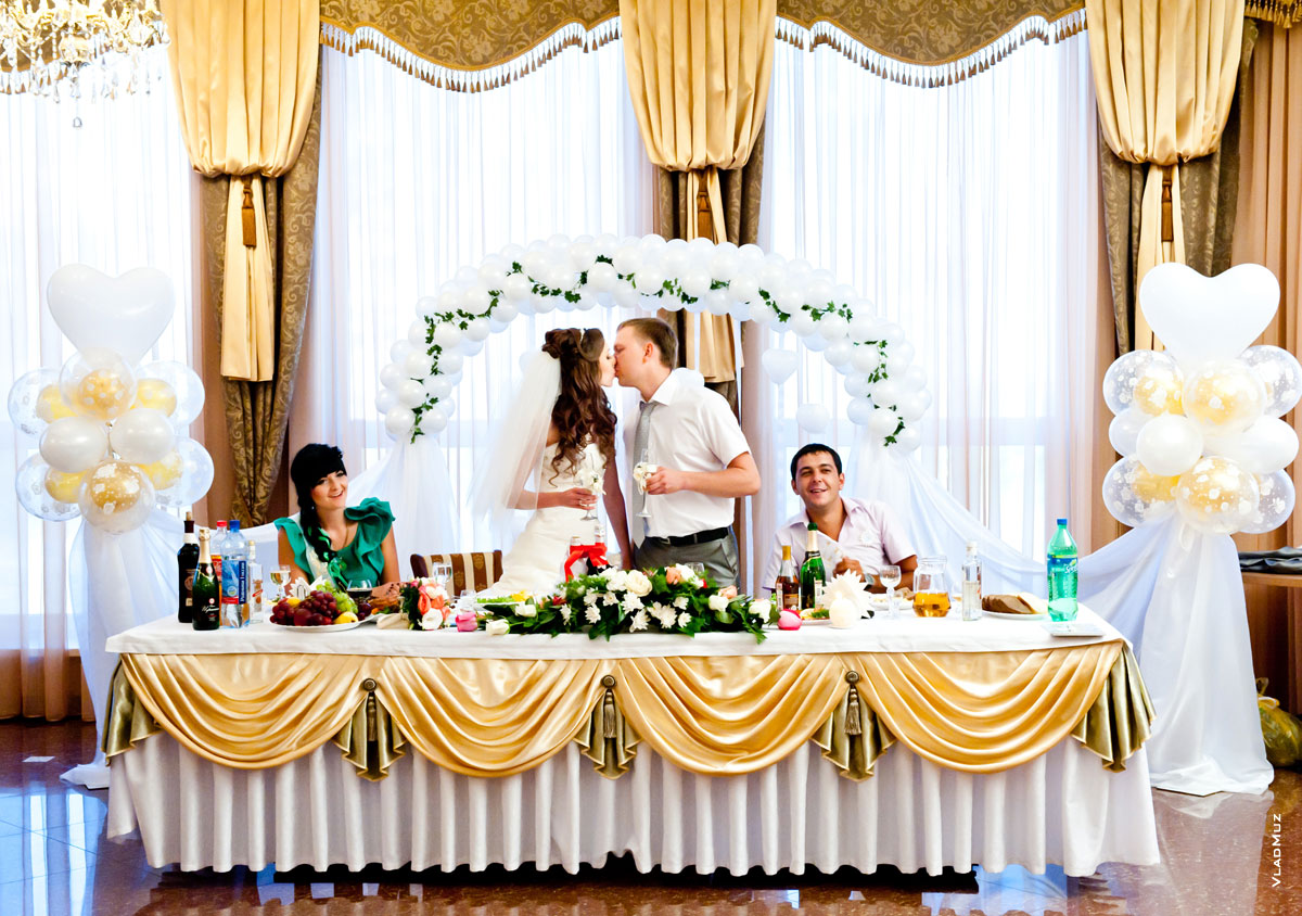 Фото поцелуя жениха и невесты за столом в ресторане
