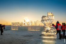 Фото ледового льва и ледяных букв «Удмуртский лед» на набережной Ижевского пруда в Ижевске в контровом свете заходящего солнца