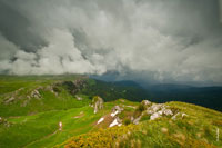 Грозовой горный фото пейзаж. Сильный ветер слева несет по склону, как по трамплину, густые облака