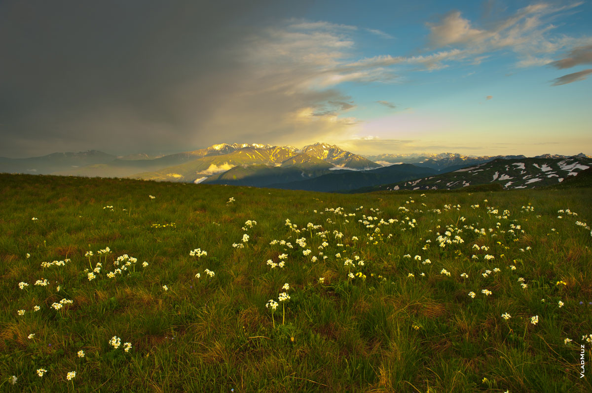 Фото горных Кавказских хребтов вдали в желтых лучах заходящего солнца