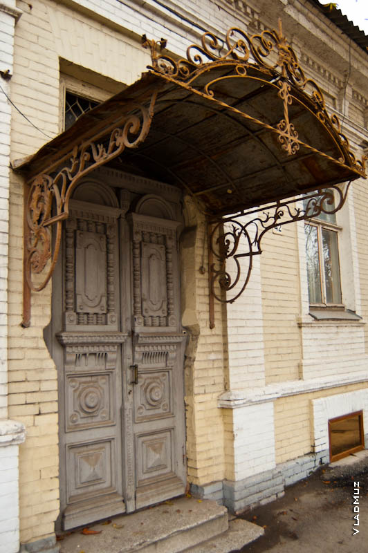 Фото старинного кованого козырька с украшенными резьбой дверьми на входе в дом в Новочеркасске