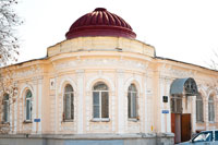 Полукруглое угловое старинное здание с куполом украшено пилястрами и декоративной лепниной
