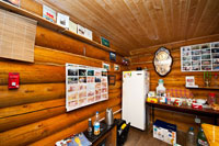 Здесь на стенах видны стенды с фотографиями, холодильник, часы, посуда и другие вещи