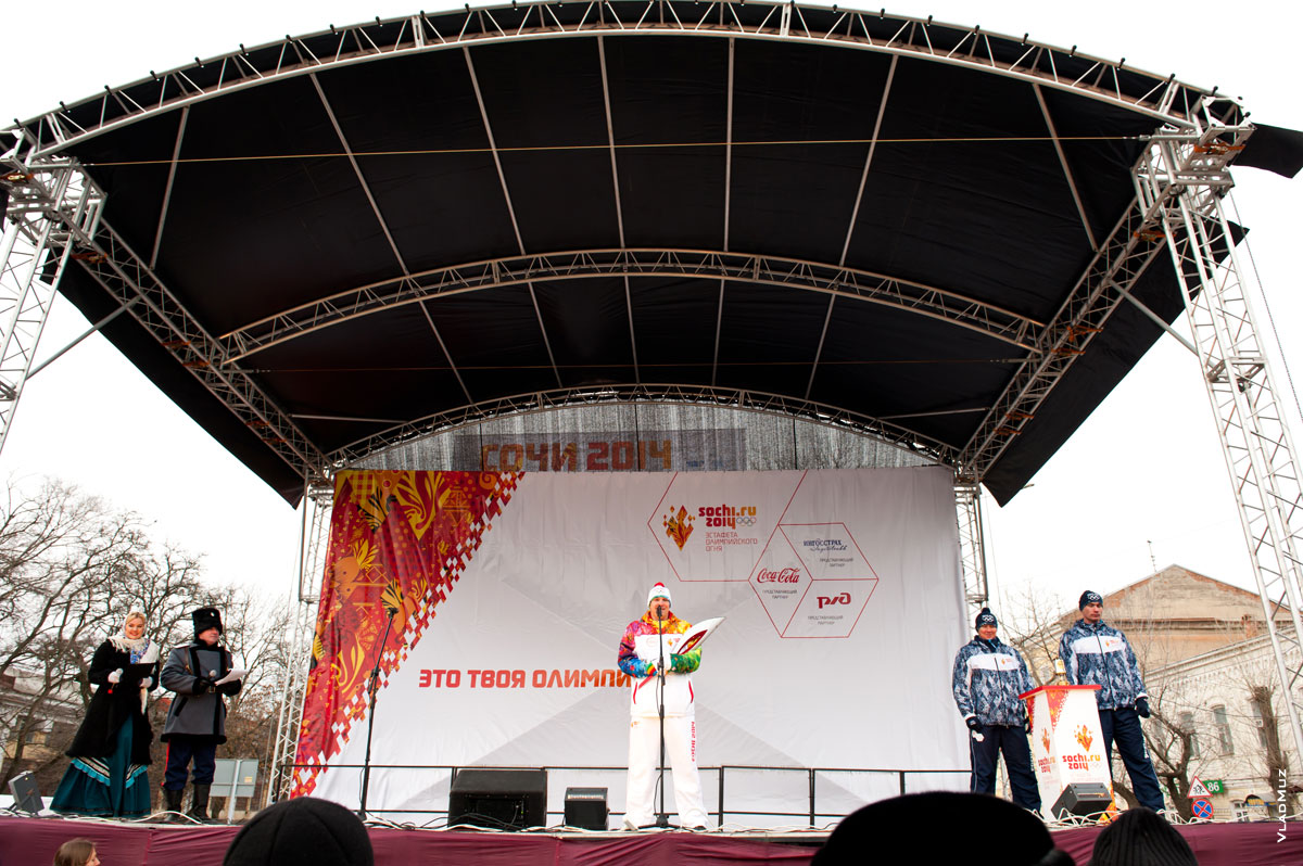 Фото факелоносца на сцене площади платова в Новочеркасске на очередном этапе эстафеты Олимпийского огня