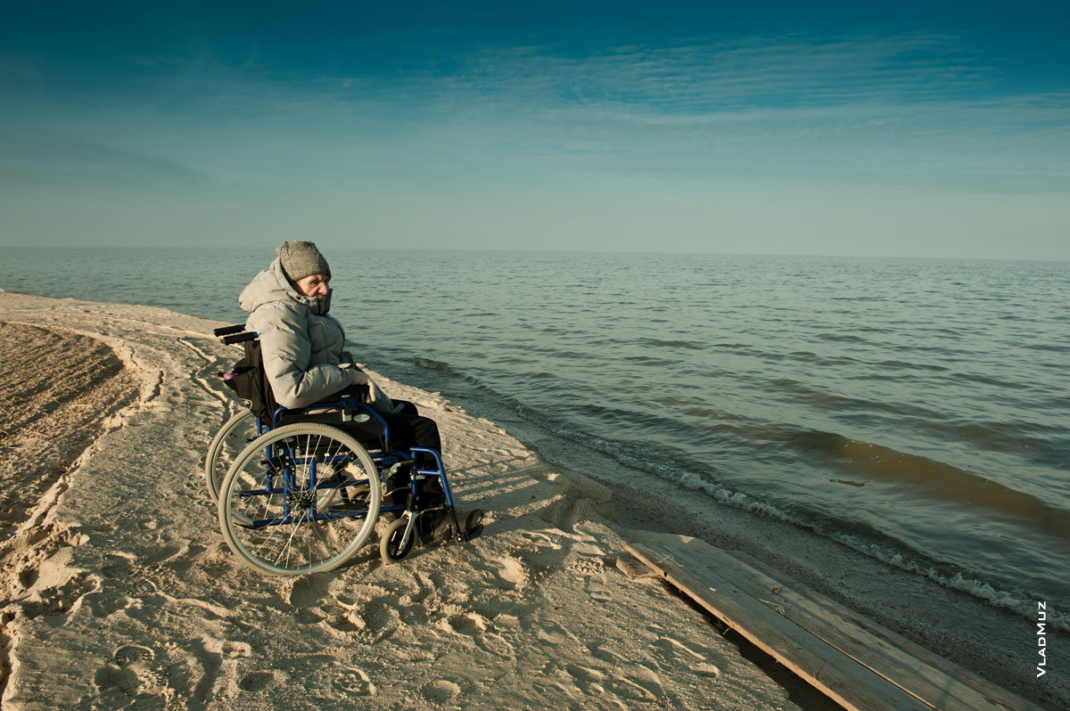 Фото мужчины в инвалидной коляске на пустынном песчаном берегу