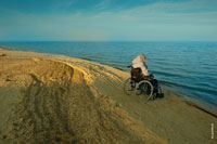 Павло-Очаковская коса, фото мужчины в инвалидной коляске на пустынном морском берегу