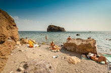 Фото Яшмового пляжа на мысе Фиолент: камни, море, отдыхающие и Георгиевская скала вдали