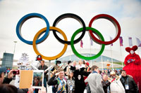 Люди фотографируются на фоне Олимпийских колец на память