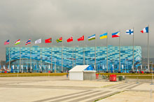 Фото флагов стран-участниц Олимпийских игр «Сочи 2014» на фоне здания дворца зимнего спорта «Айсберг»