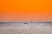 Морской фотопейзаж: катер «Авега» и яхты на горизонте в море после заката