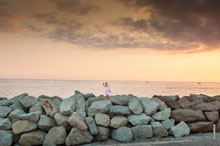Фото девушки с телефоном на каменистой набережной Имеретинского морского порта в Адлере (Сочи)