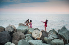 Фото 3-х девушек на каменистой набережной Имеретинского морского порта, фотографирующихся телефонами
