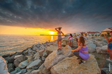 Фото девушек, фотографирующихся на закате, на фоне Имеретинского морского порта Адлера