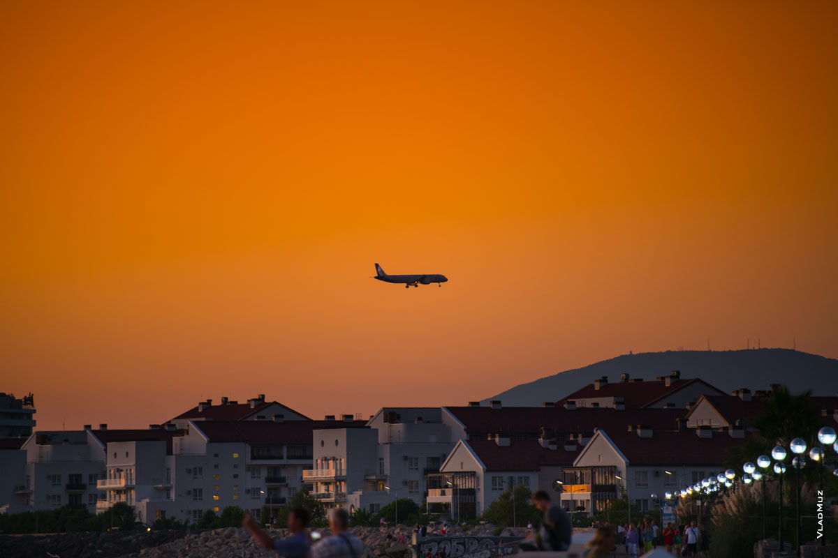 Фото самолета в небе Адлера над Морским кварталом. Фотопейзаж после заката солнца