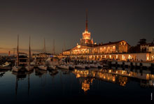 Ночное фото здания Морского вокзала с подсветкой и яхты у причала
