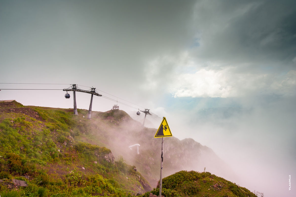 «Роза Хутор» в Сочи летом на высоте «Роза Пик»: фото предупреждающего знака «Опасно-Обрыв» и подъемника вдали в облаках